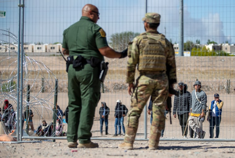 Migrantes hacen fila junto a la valla fronteriza bajo la supervisión de la Patrulla Fronteriza y la Guardia Nacional de Texas para ingresar a El Paso, Texas, el 10 de mayo de 2023. 