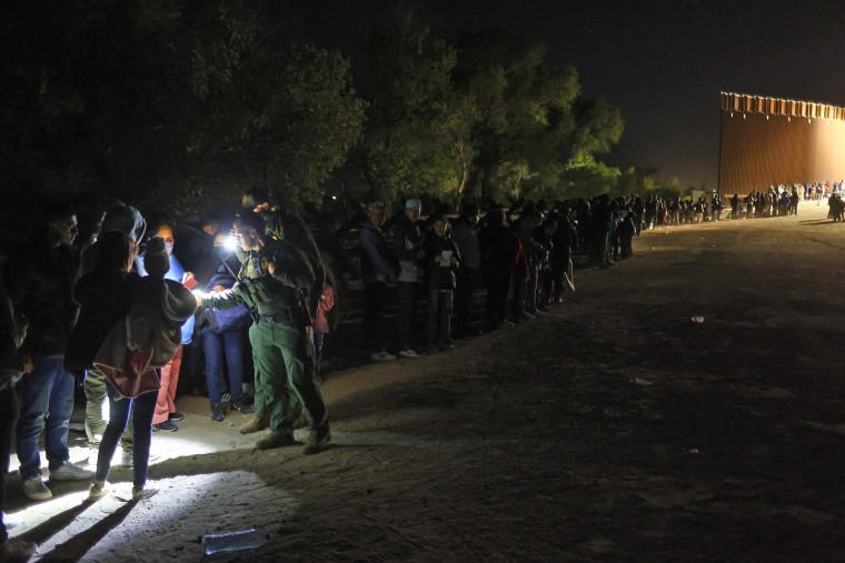 Asylum-seekers stand in line as they are processed by U.S. Border Patrol agents early on May 10, 2023, after crossing into Yuma, Ariz., from Mexico.