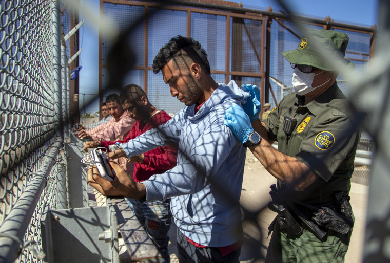 Migrants are pat down by a Border Patrol agent as they enter into El Paso, Texas