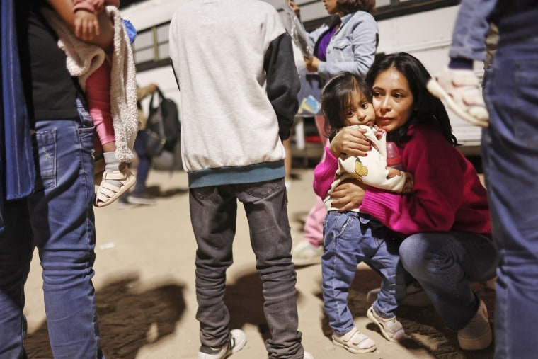 Peruvians seeking asylum in the U.S. wait to board a bus during processing by U.S. Border Patrol agents after crossing into Yuma, Ariz., from Mexico early on May 11, 2023.