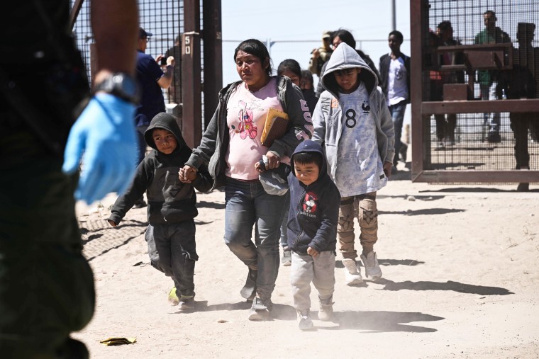Migrants with children walk to board a bus after surrendering to US Customs and Border Protection Border Patrol agents 