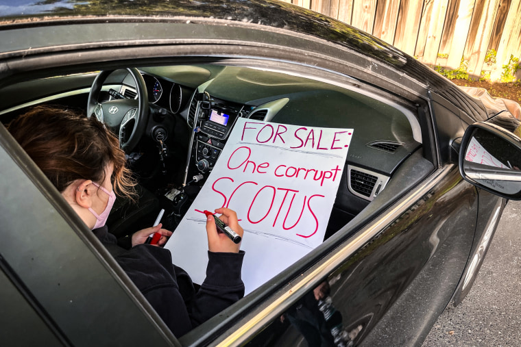A woman prepares a sign critical of the Supreme Court before joining a protest outside the homes of Justice Brett Kavanaugh and Chief Justice John Roberts on May 4, 2023.