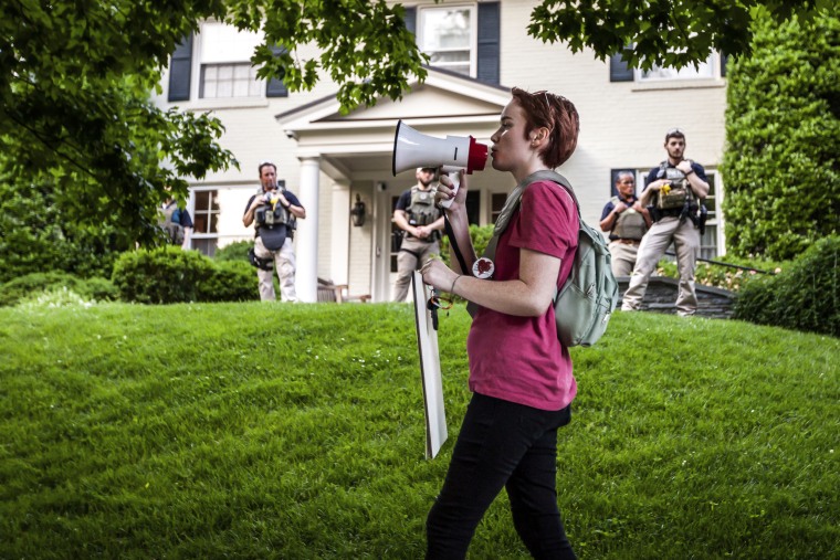 Federal marshals stand guard as a pro-choice protester marches past at Supreme Court Chief Justice John Roberts' house in Chevy Chase, Md., on May 18, 2022.