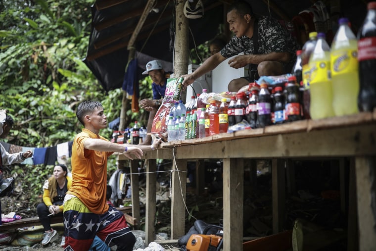 Image: A Venezuelan migrant buys an energy drink at a stall set up along the route of the Darien Gap, from Colombia into Panama, on May 9, 2023. 