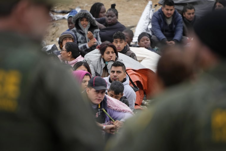 People line up as they wait to apply for asylum between two border walls on May 12, 2023, in San Diego. 