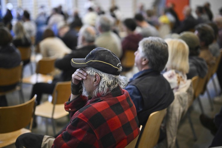 Un hombre se tapa los ojos con la mano durante la reunión informativa a la población sobre la evacuación del pueblo de Brienz-Brinzauls bajo el "Brianz Rütsch"en Tiefencastel el martes 9 de mayo de 2023. Suiza. 