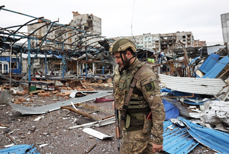 An Ukrainian serviceman walks near residential buildings damaged by shelling in Bakhmut, Ukraine