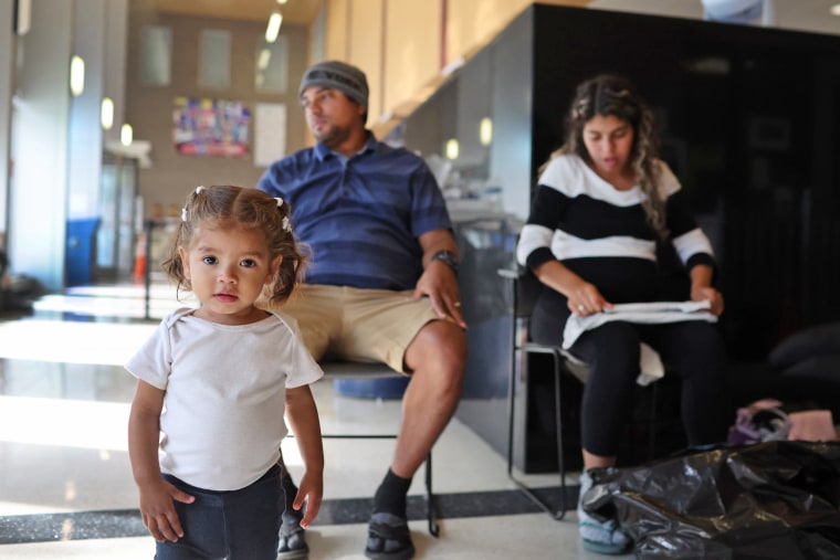 A couple from Venezuela and their 17-month-old daughter rest in the lobby of a police station in Chicago on May 9, 2023, where they have been staying with other migrant families since their arrival in the city.