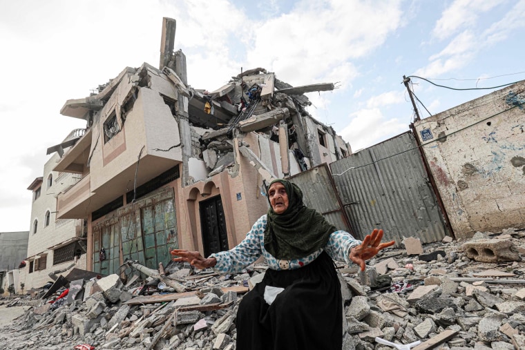 An elderly woman gesticulates among the rubble of a destroyed building in the Gaza Strip