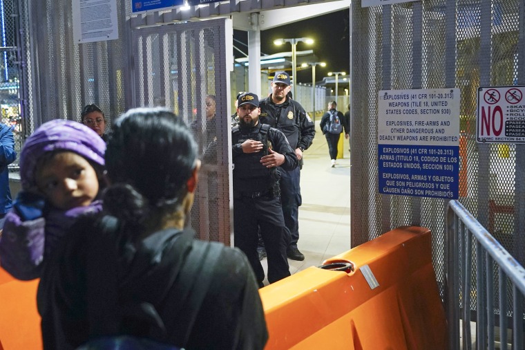 A migrant speaks to U.S. Customs and Border Protection officials at a gate entrance