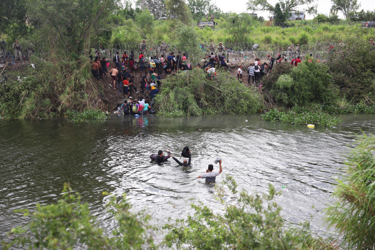 Migrants cross the Rio Grande in Matamoros, Mexico while traveling to the United States border,
