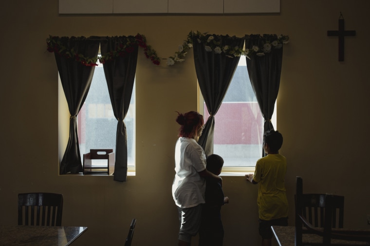 Rosa looks out the window of the El Paso Rescue Mission in El Paso with her six and nine year old children