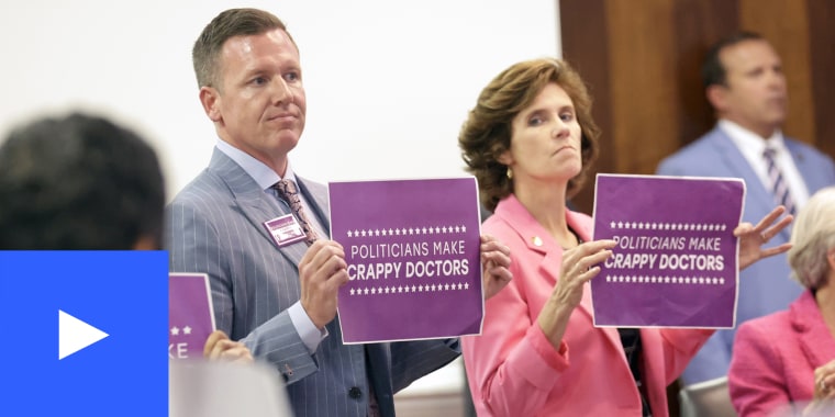 Democratic Sens. Michael Garrett, holding sign at left, and Natasha R. Marcus, and other Democrats hold signs in protest, Tuesday, May 16, 2023, in Raleigh, N.C., after the state Senate voted to override Democratic Gov. Roy Cooper's veto of a bill that would change the state's ban on nearly all abortions from those after 20 weeks of pregnancy to those after 12 weeks of pregnancy. Both the Senate and House had to complete successful override votes for the measure to be enacted into law.