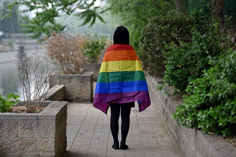 A gay student poses with a rainbow flag in Beijing in 2019.