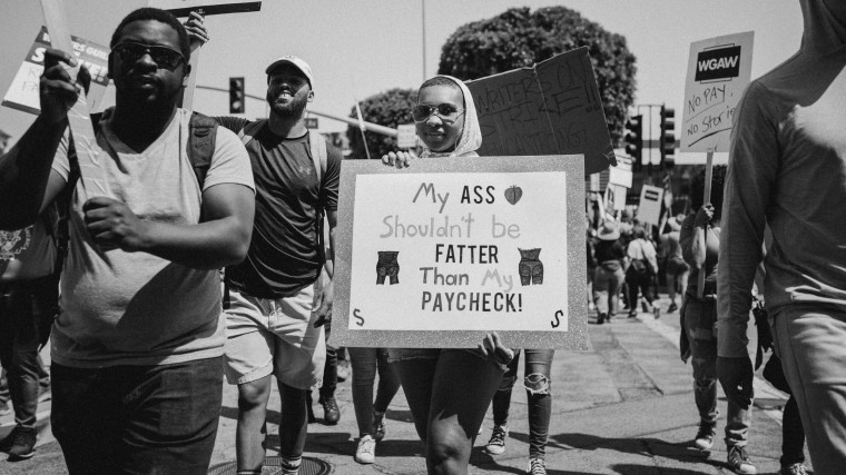 Kyra Jones holds signs while striking with the Writer's Guild of America.