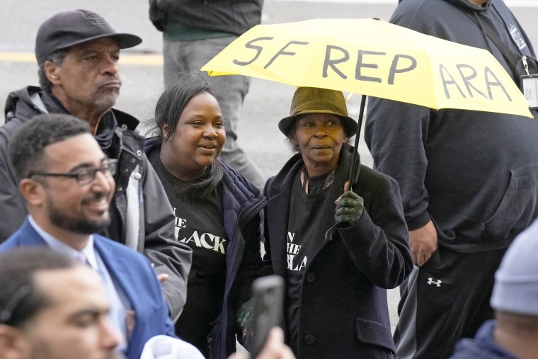 Pia Harris and Adrian Williams, listen to speakers at a reparations rally outside of City Hall in San Francisco
