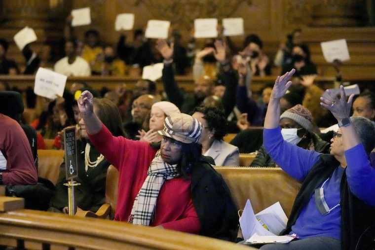 People react to speakers during a Board of Supervisors hearing about reparations in San Francisco