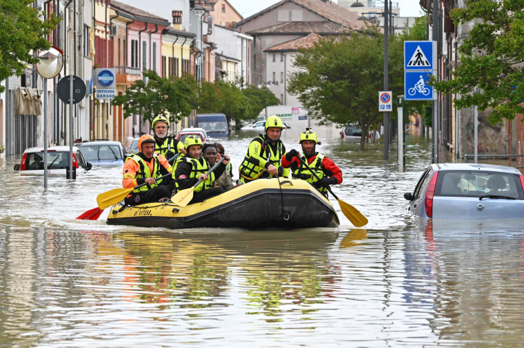 Rescuers evacuate residents in a dinghy across a flooded street in Lugo, Italy