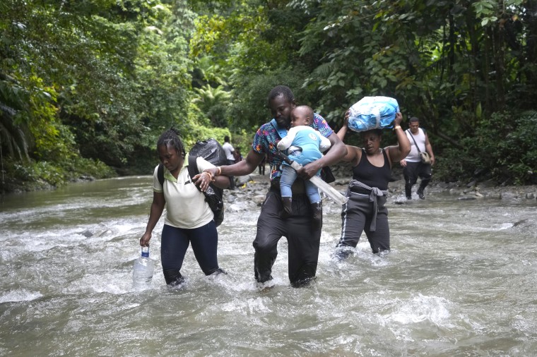 Haitian migrants walk through a river as they cross the Darien Gap