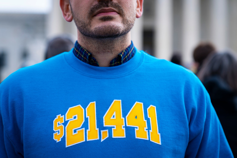 Cody Hounanian, executive director at the Student Debt Crisis Center, in a sweatshirt with the amount he owed in student loans  during a protest in support of student debt cancellation as the Supreme Court begins oral arguments on Feb. 28, 2023.