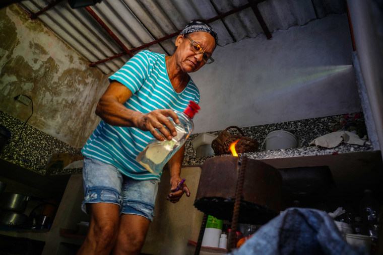 Rosa Lopez lights a charcoal stove to cook food for her grandchildren, amid a gas shortage in Mariel, Cuba, on May 18, 2023. 