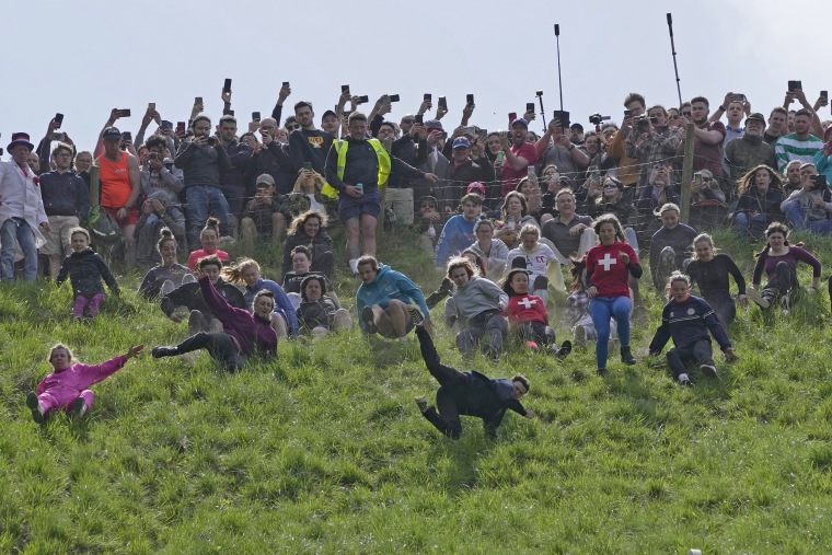 Participants compete in the women's downhill race during the Cheese Rolling contest at Cooper's Hill in Brockworth, Gloucestershire, Monday, May 29, 2023.