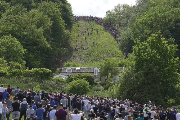 Participants compete in the downhill race during the Cheese Rolling contest at Cooper's Hill in Brockworth, Gloucestershire, Monday May 29, 2023. 