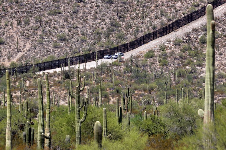 ARCHIVO - Oficiales de Aduanas y Patrullas de EE. UU. sentados a lo largo de una sección del Muro Fronterizo Internacional que atraviesa el Monumento Nacional Organ Pipe Cactus, el jueves 22 de agosto de 2019, en Lukeville, Arizona.  hombre en una reserva tribal en el sur de Arizona después de arrojar algo repentinamente y levantar el brazo, dijo la agencia el lunes 22 de mayo de 2023.