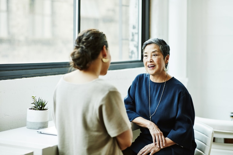 Smiling businesswoman in discussion with another woman in office.