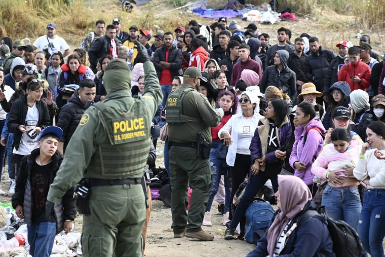 Agentes de la Patrulla Fronteriza entregan brazaletes a un grupo de migrantes que buscan asilo en Estados Unidos en la frontera con Tijuana, México.
