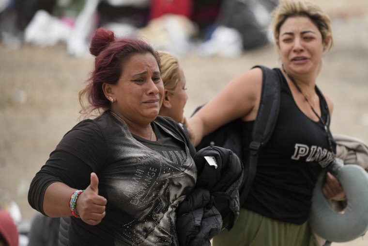 Dos mujeres reaccionan tras escogidas por agentes de la Patrulla Fronteriza de Estados Unidos para ser procesadas en la frontera con México, el viernes 12 de mayo de 2023.

