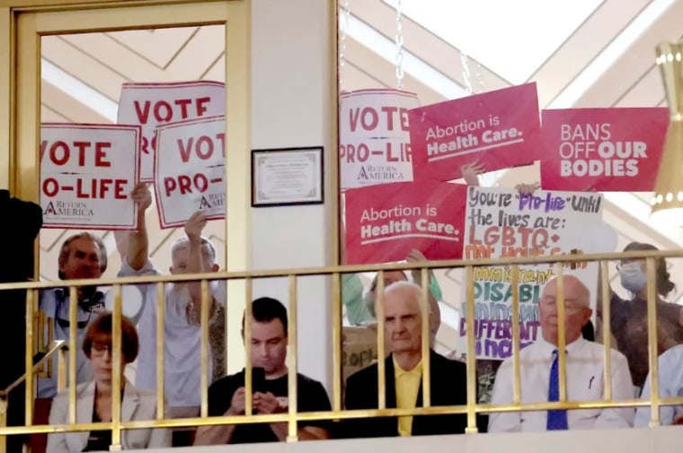 Manifestantes de ambos bandos sostienen pancartas mientras miembros de la Cámara de Representantes de Carolina del Norte debaten en Raleigh, Carolina del Norte, el martes.