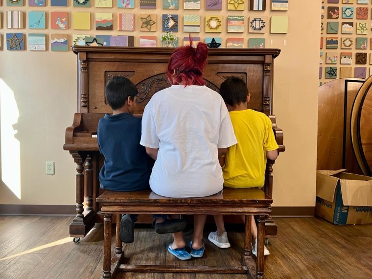 Rosangel se sienta junto a dos de sus hijos en el piano del comedor del albergue en El Paso, Texas, el 12 de mayo.