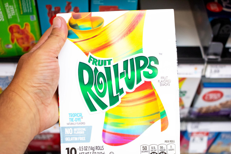 A view of a hand holding a box of Fruit Roll-ups at the grocery store.