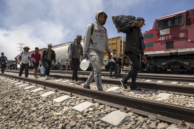 Inmigrantes caminan después de desembarcar de un tren de carga en ruta a la frontera entre Estados Unidos y México el 10 de mayo de 2023 cerca de Ciudad Juárez, México.