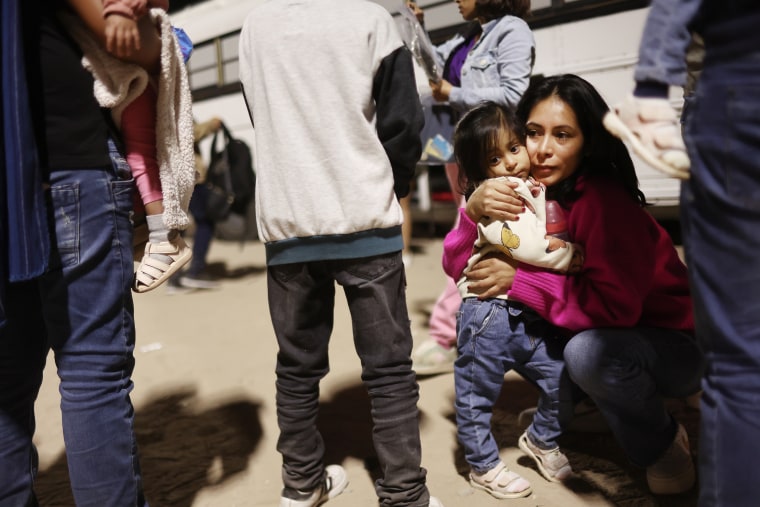 Familiares de inmigrantes peruanos que buscan asilo en los Estados Unidos se abrazan mientras esperan para abordar un autobús mientras son procesados por agentes de la Patrulla Fronteriza de Estados Unidos en la madrugada después de cruzar a Arizona desde México el 11 de mayo de 2023 en Yuma, Arizona.