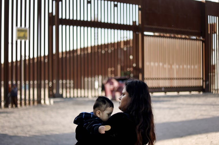 Miriam, una madre peruana, se encuentra con su hijo Andre, cerca de otros miembros de la familia que buscan asilo en los Estados Unidos, mientras esperan ser procesados por agentes de la Patrulla Fronteriza de los Estados Unidos después de cruzar a Arizona desde México el 12 de mayo de 2023 en Yuma, Arizona.