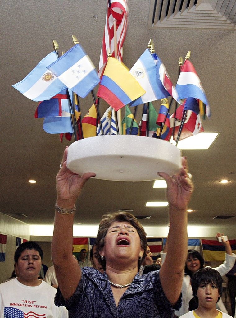 Una mujer llamada Magdalena Schwartz sostiene un grupo de banderas de los países centroamericanos durante un servicio religioso en la iglesia Palabra de Vida en Mesa, Arizona, en 2006