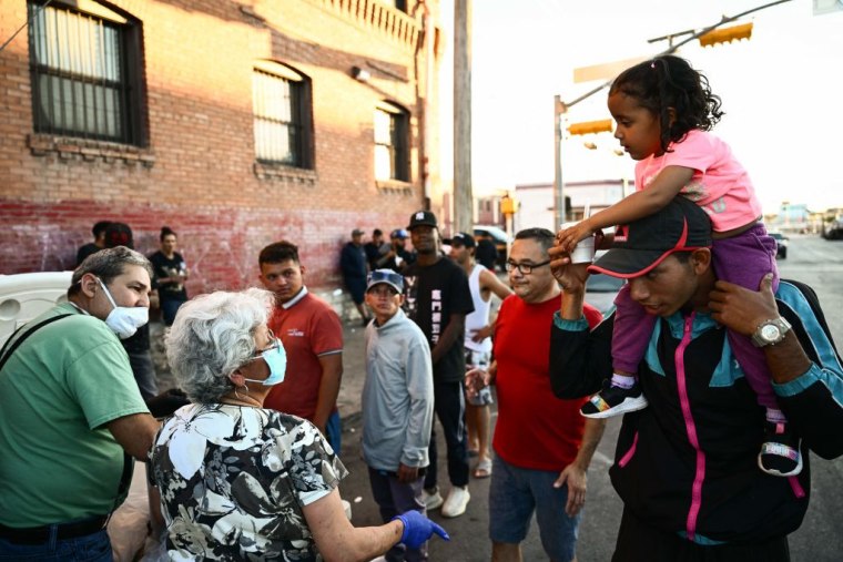 Personas distribuyeron alimentos a los migrantes que se reunieron afuera de la iglesia del Sagrado Corazón en El Paso, Texas, el 8 de mayo de 2023. 
