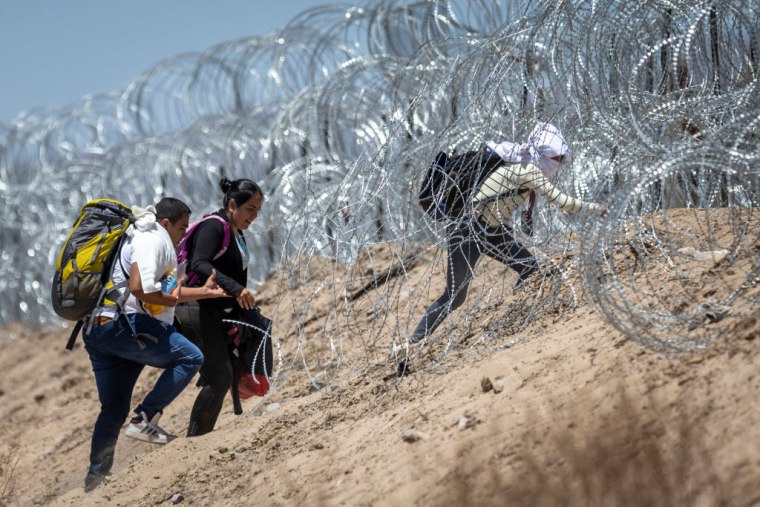 Migrantes atraviesan alambre de púas para cruzar la frontera de México con Estados Unidos en El Paso, Texas, el 11 de mayo de 2023.