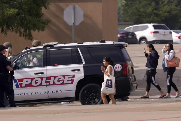 Transeúntes alzan las manos mientras pasan cerca de la policía en el estacionamiento del centro comercial Allen Premium Outlets, en Texas, el 6 de mayo de 2023.