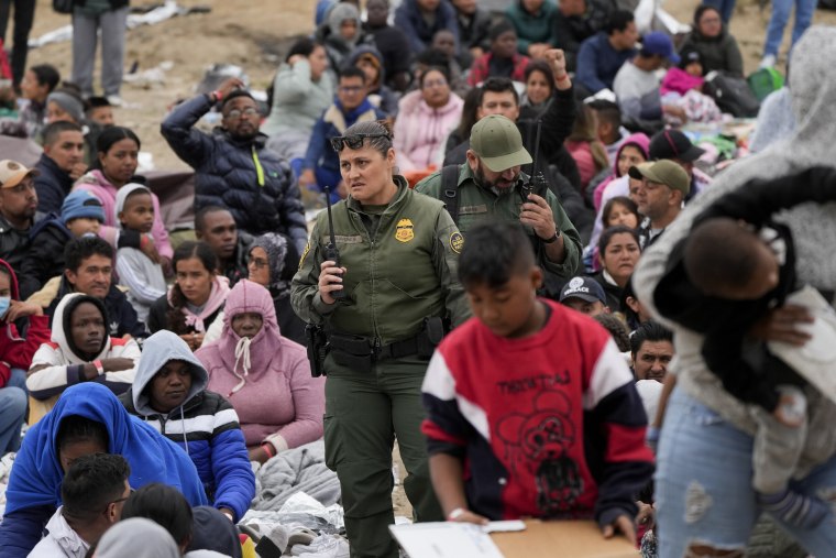 Agentes de la Patrulla Fronteriza avanzan en medio de migrantes que esperan a pedir asilo en una punto fronterizo de San Diego, California, este viernes 12 de mayo.