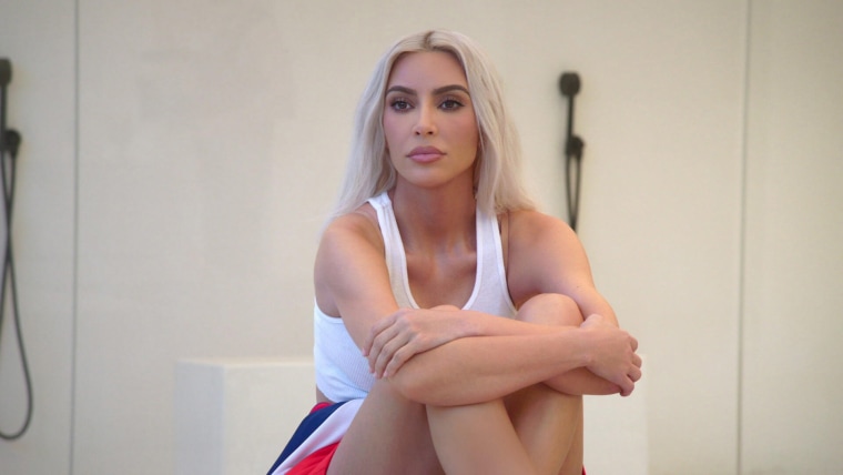 Kim Kardashian est assise sur un comptoir dans un débardeur blanc.