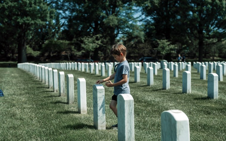 A child volunteers for "The Honor Project," visiting gravesites of military members buried in Arlington National Cemetery in 2022.