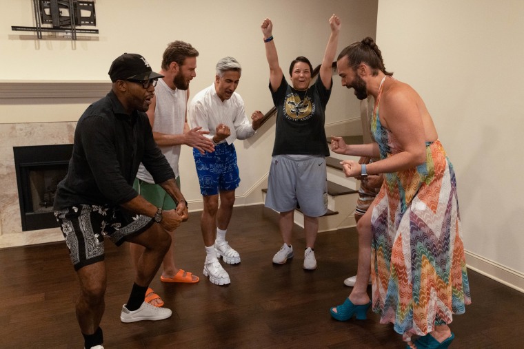 A group of people stand in a home and cheer together.