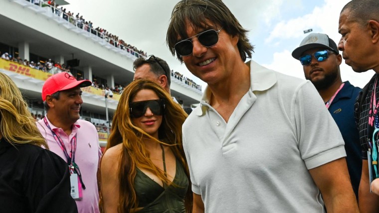 Shakira y Tom Cruise sonríen ante la cámara en evento deportivo.