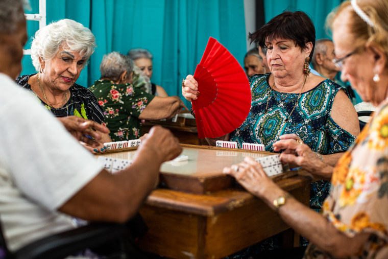 Olga Ayala, 91, left, Emely Santana, 71, center, and Hilda R. D’az, 87, play dominoes at the Center for Activities and Multiple Uses for the Elderly of Toa Baja in Toa Baja, Puerto Rico, on May 26, 2023.