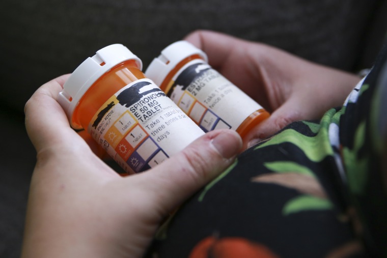 Sage Chelf holds bottles of medications for hormone replacement therapy as part of her gender affirming care as a trans woman at home in Orlando Fla., May 27, 2023. 