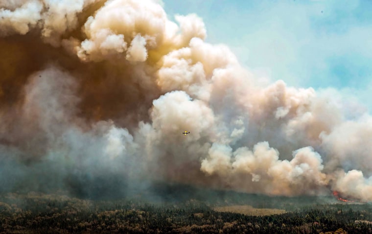 Image: One of eight aircrafts from New Brunswick that drops a mix of water and fire retardant makes a pass over the fire near Barrington Lake, Shelburne County, Nova Scotia province on May 31, 2023.