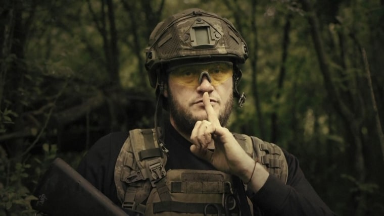 A Ukrainian soldier poses for the camera with his fingers to his lips, in an undisclosed location in Ukraine.